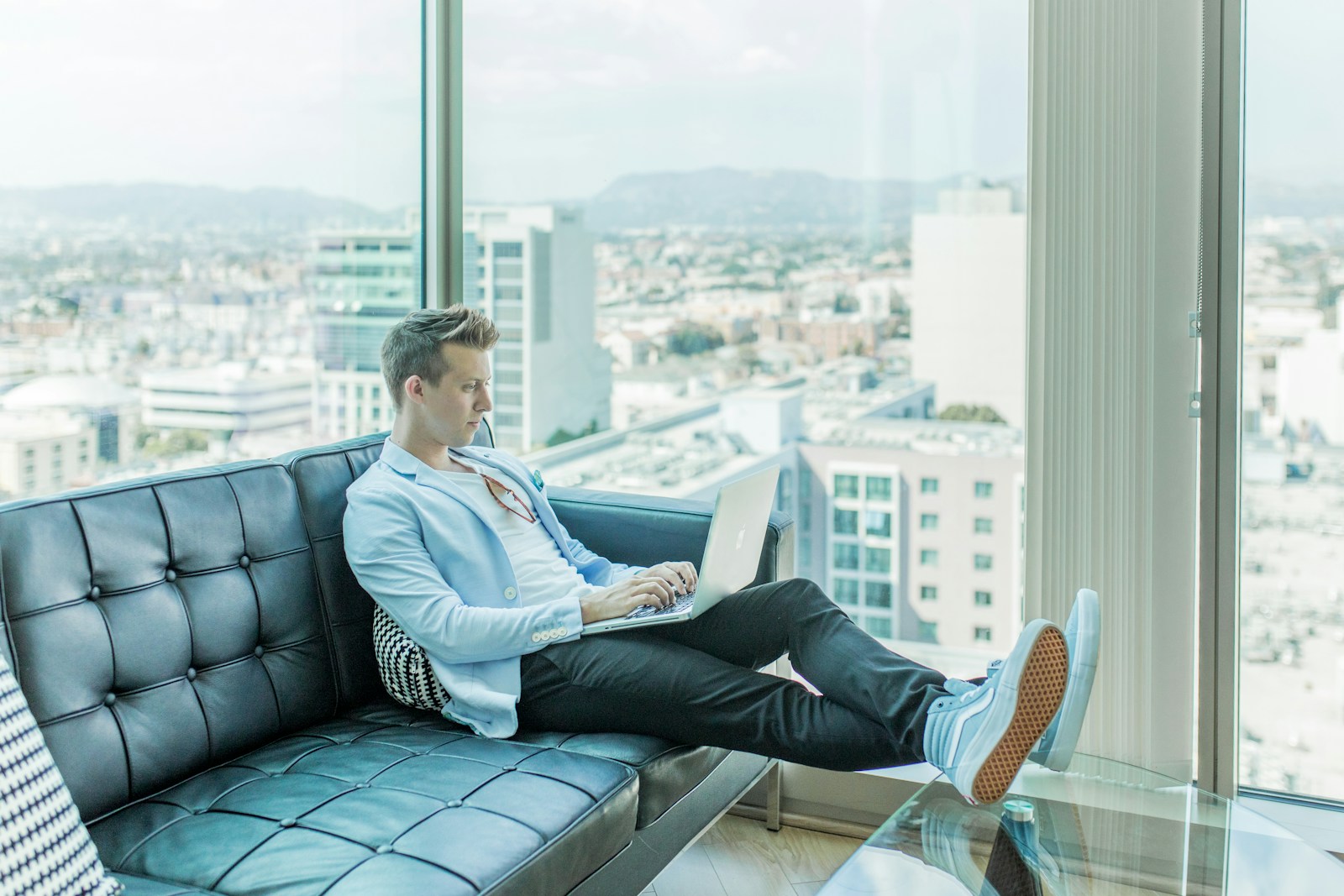 Mann sitzt auf dem Sofa und benutzt einen Laptop